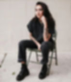 a young woman wearing black clothes and doc marten boots sitting on a folding chair
