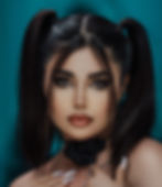 woman with high pigtails and tendrils of hair in the front posing in front of a blue wall