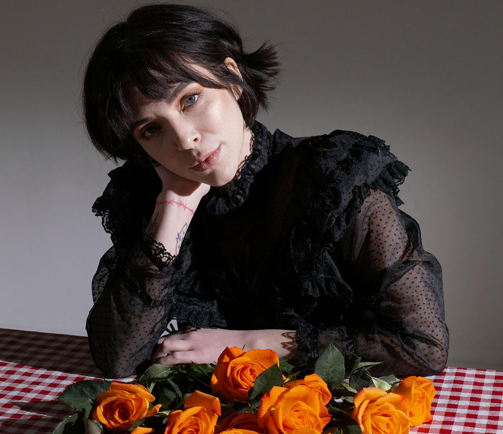 a woman in a lacy black long sleeve blouse sitting at a picnic table with roses.