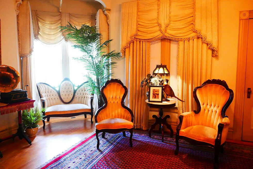 a victorian sitting room with yellow walls, two orange chairs, a settee, and a potted palm