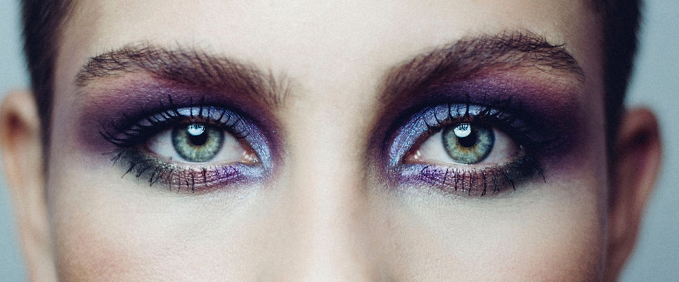 close up of a model with green eyes wearing purple iridescent eyeshadow