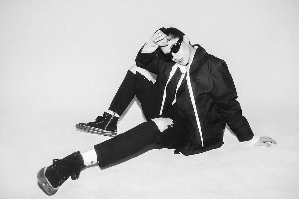 A woman in ripped black pants, sneakers, and a blazer