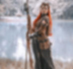 a woman in dark robes and makeup holding a staff