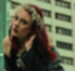 woman posing outside in a city with a crown of pearls and long red hair