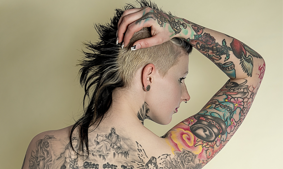A woman with tattoos and piercings shows off her mohawk from behind