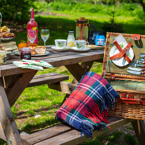 An afternoon tea for 2 laid out on the picnic table with afternoon tea and picnic hamper box. Can be delivered to your lodge ready for your arrival.