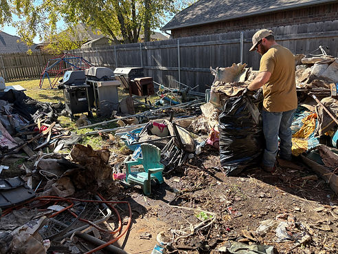 Man cleaning a trash-filled backyard