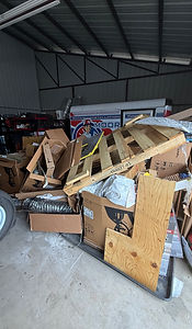 Cluttered storage unit with boxes, pallets, and a tire.