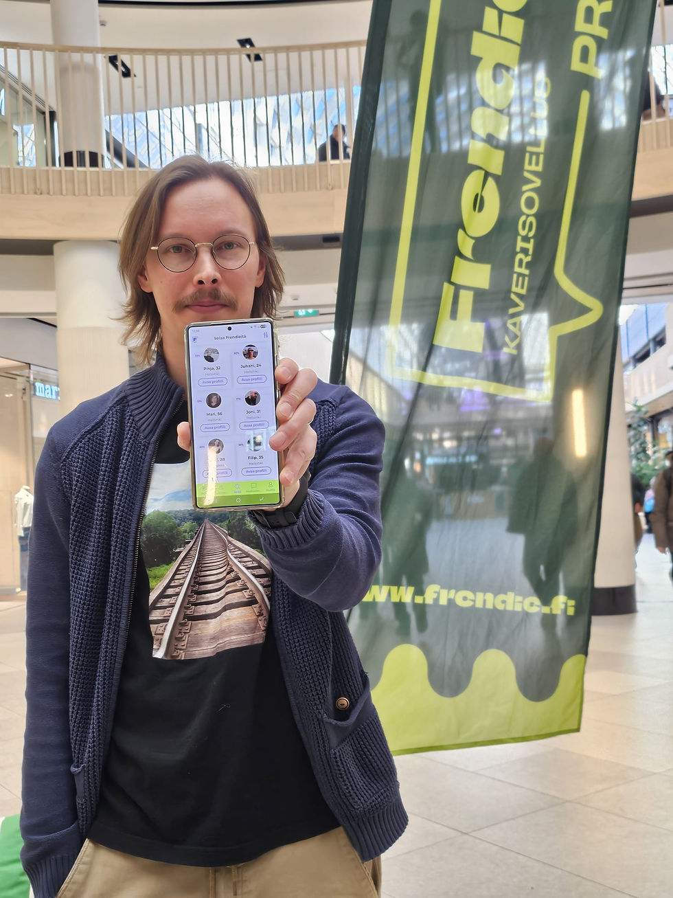 Ville näyttää Frendie kaverisovellusta kameralle Itiksessä Frendien bannerin edessä