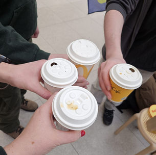 Neljä ihmistä pitelee kertakäyttökahvikuppeja niin, että heistä näkyy vain kädet jotka pitelevät kuppeja