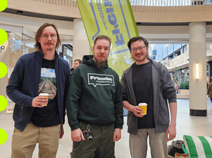 Valokuvassa kolme miestä kauppakeskus Itiksessä, Frendien bannerin edessä, hymyilevät kameralle. Kaksi heistä pitelevät kertakäyttöisiä kahvikuppeja ja yhdellä on Frendie-huppari.