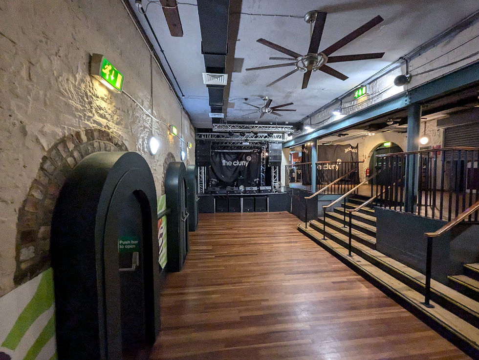 A long, low ceilinged room with a stage at the far end