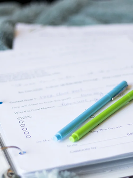 Notebook with handwritten goals and pens on a desk