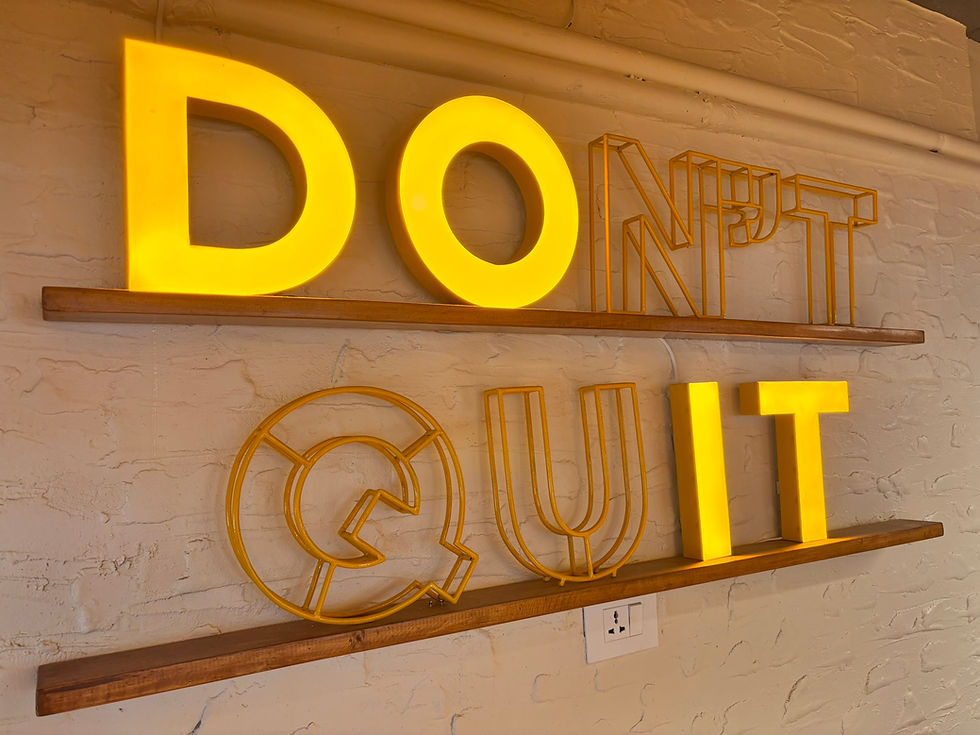 A motivational wall sign in bold yellow lettering reading “DON’T QUIT,” creatively styled so the lower row reads “DO IT” when viewed differently.