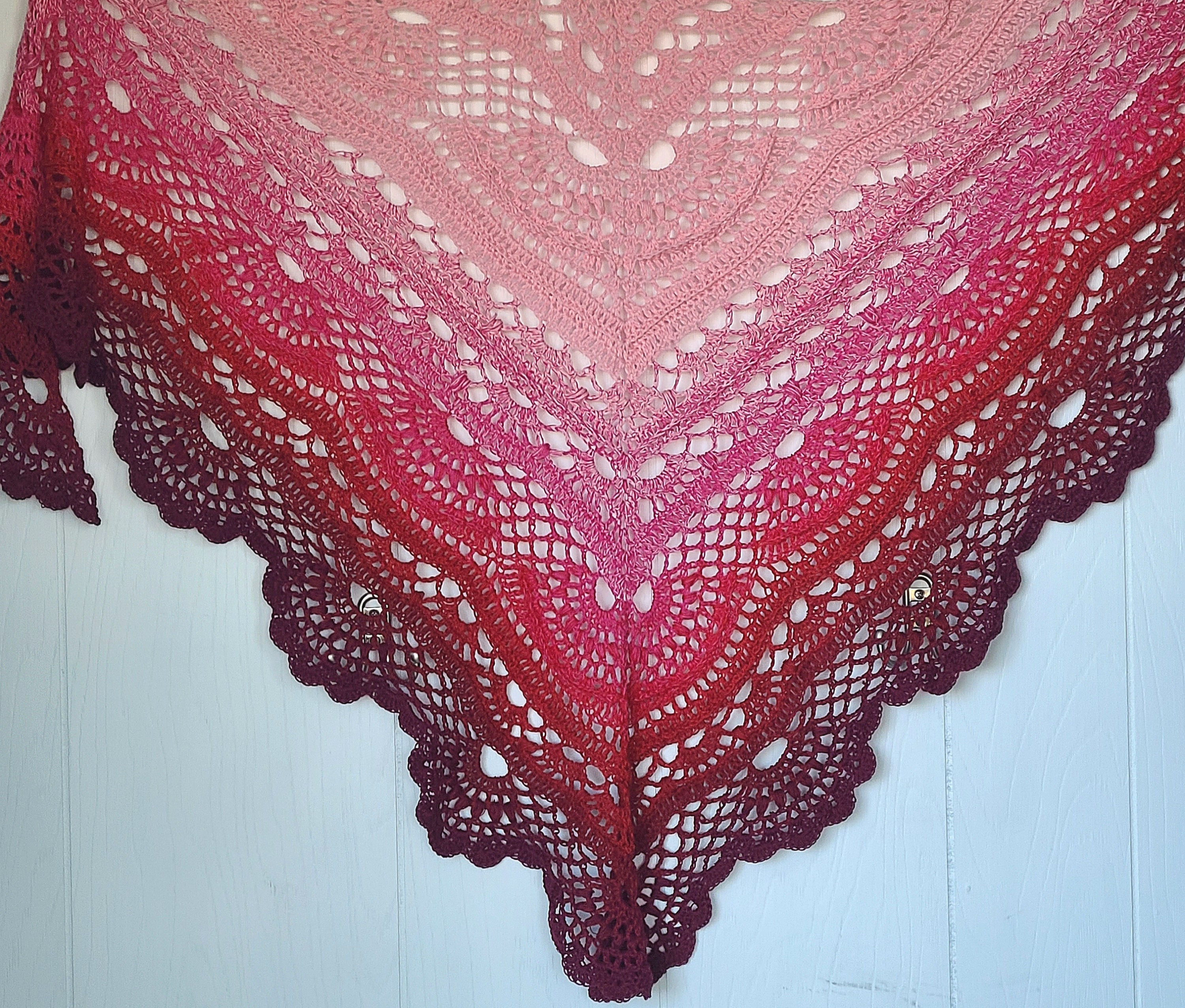 frontal view of a pink to wine red colored triangle lace shawl