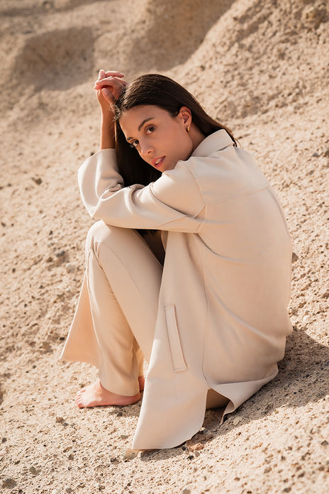 Laura Lopez model Spain barefoot posing on rocks wearing elegant light cream tailored pantsuit jacket and trousers Salitre Models