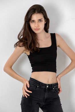 Studio polaroid photoshoot of female high-fashion model Laura Jimenez wearing a black tank top and slim black jeans for casting digitals.