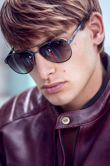 Leonardo Russo new face male model wearing a burgundy leather jacket with white stripes riding a Royal Enfield motorcycle with Prada aviator sunglasses Salitre Models