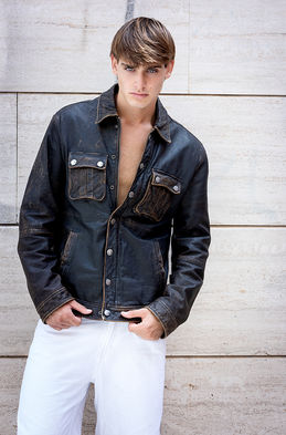 Leonardo Russo new face male model wearing a brown distressed Armani leather jacket with chest pockets and white trousers outdoor fashion shoot Salitre Models