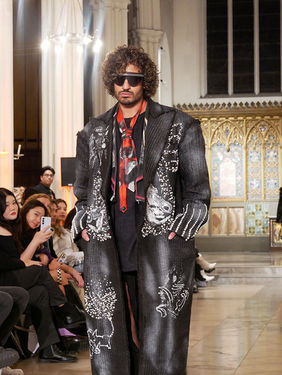 Professional male model Reda Akalay showcasing a high-fashion designer look on the runway at London Fashion Week.