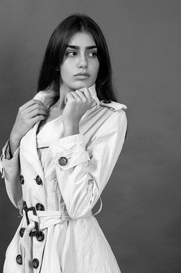 Yashira Suárez posing in a structured, fully buttoned trench coat during a studio fashion photoshoot – Female model portfolio for Salitre Models.