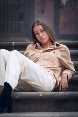 Outdoor portrait of female model Sara Jimenez wearing a loose, oversized white button-up shirt and wide-leg white trousers.