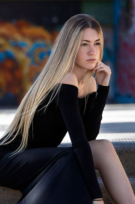 Outdoor portrait of female model Sara Jimenez wearing a fitted black suit, showcasing her long, sleek straight blonde hair.