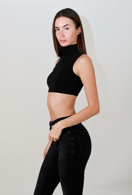 Model Lorena Nicoleta posing in a studio wearing a black sleeveless crop top and tight-fitting black pants.