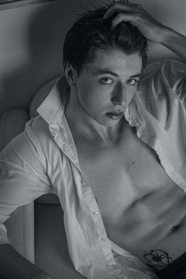 Alexis Alamo, male model in Canary Islands, lying on a sofa with an unbuttoned shirt in a black and white overhead fashion shoot.