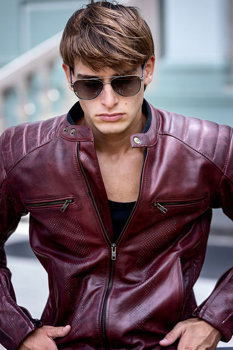 Leonardo Russo new face male model wearing a burgundy leather jacket with white stripes riding a Royal Enfield motorcycle with Prada aviator sunglasses Salitre Models