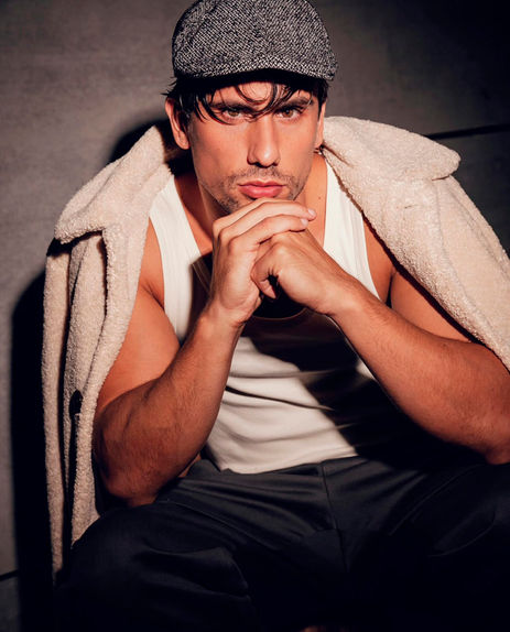 Alberto Pelaez professional male model color photography rustic heritage style wool jacket flat cap beret white tank top dark moody background low key lighting Salitre Models.
