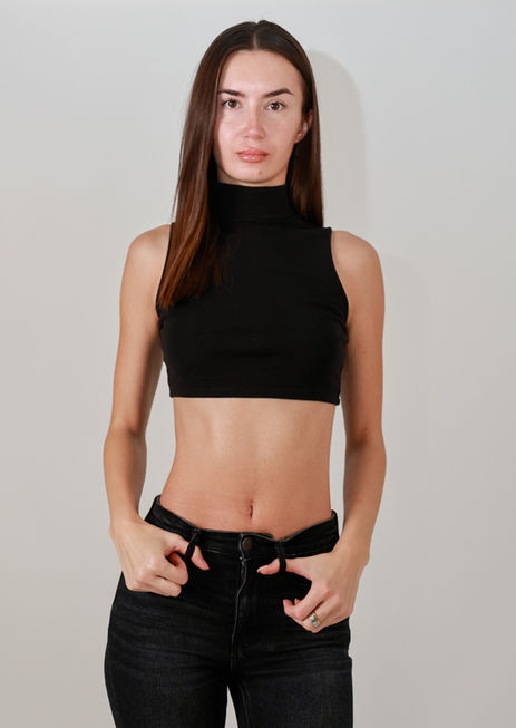 Model Lorena Nicoleta posing in a studio wearing a black sleeveless crop top and tight-fitting black pants.