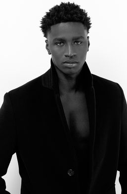 Omar Diop posing shirtless under a dark blue overcoat with black pants in a studio fashion photoshoot – Male model portfolio for Salitre Models.