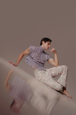 Alexis Alamo, professional male model in Canary Islands, posing for a subtle and romantic studio shoot with a pink sleeveless lace top and cream trousers.