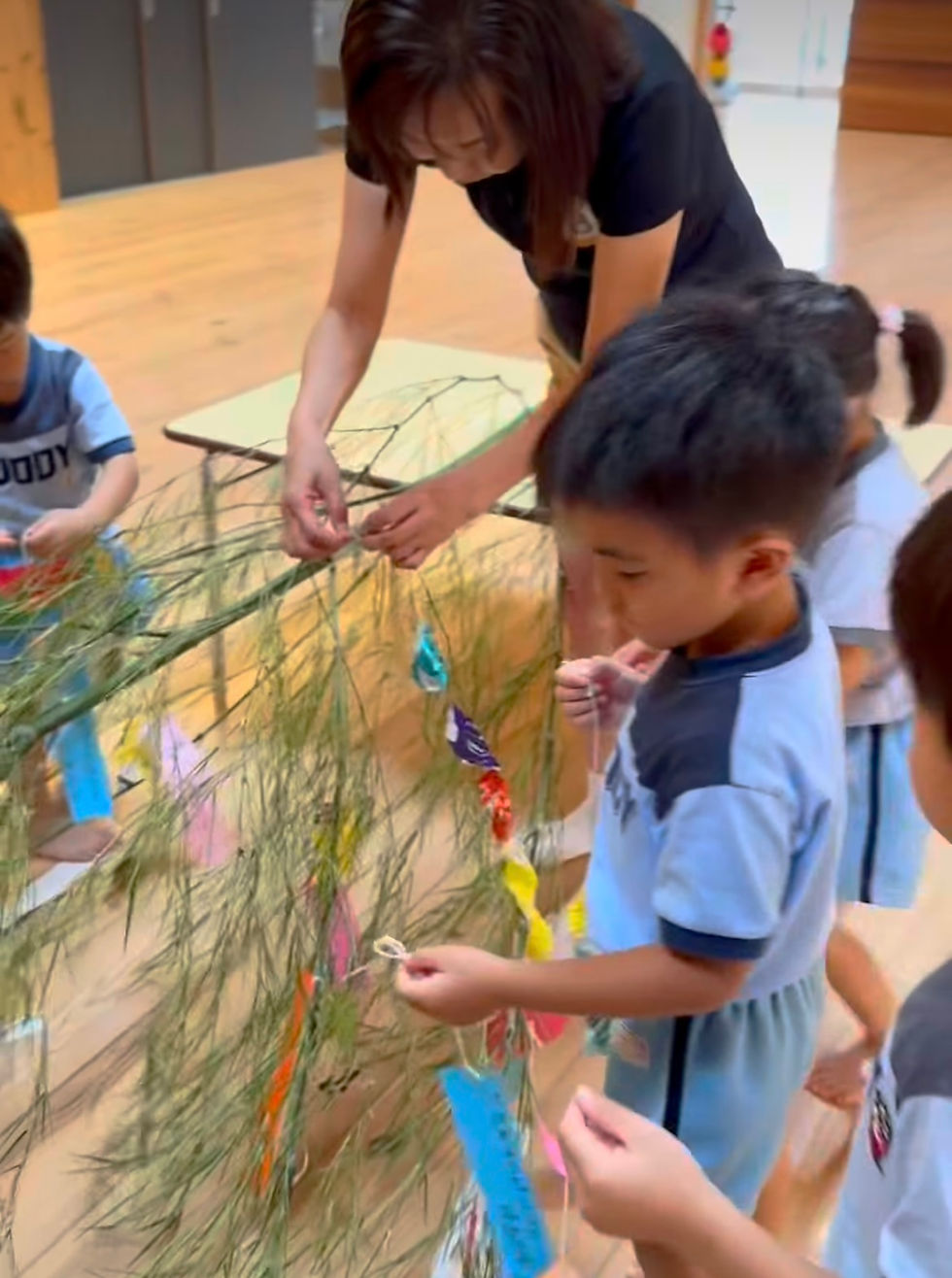 笹の葉にお願い事を書いた短冊を飾りつける子ども達