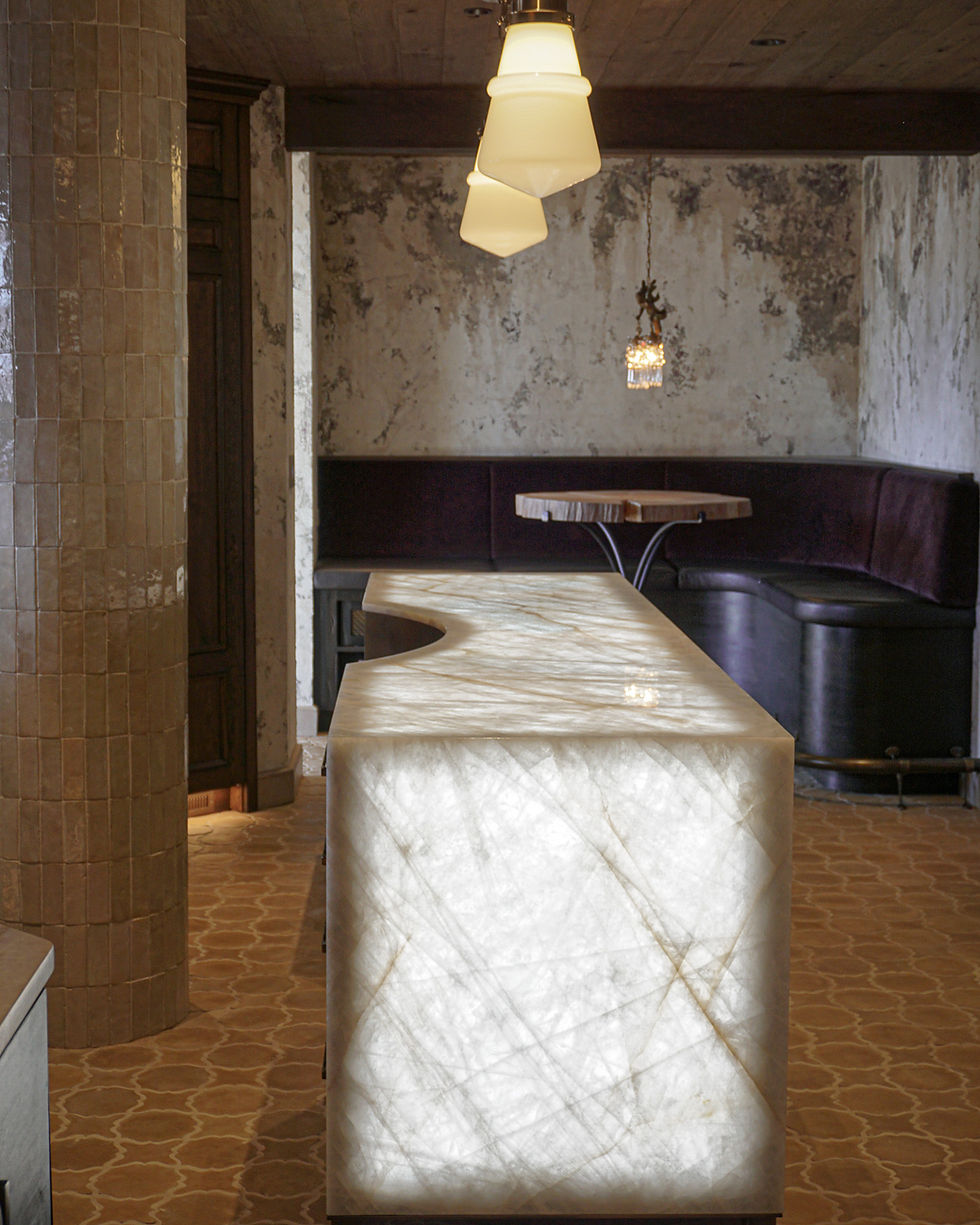 Backlit translucent stone island with natural veining in a modern lounge.