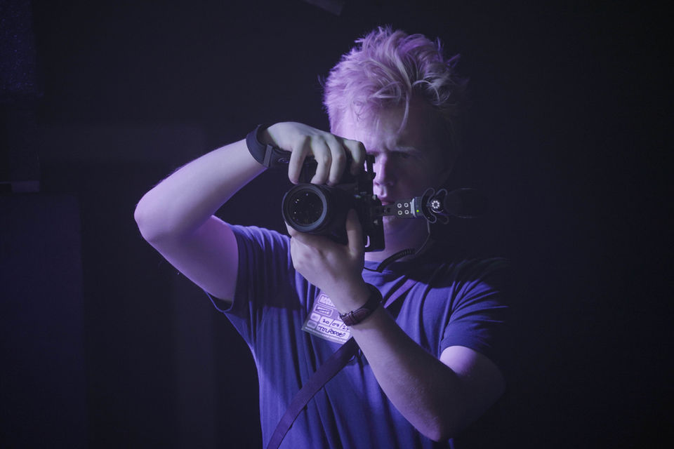 man holds camera, purple glow