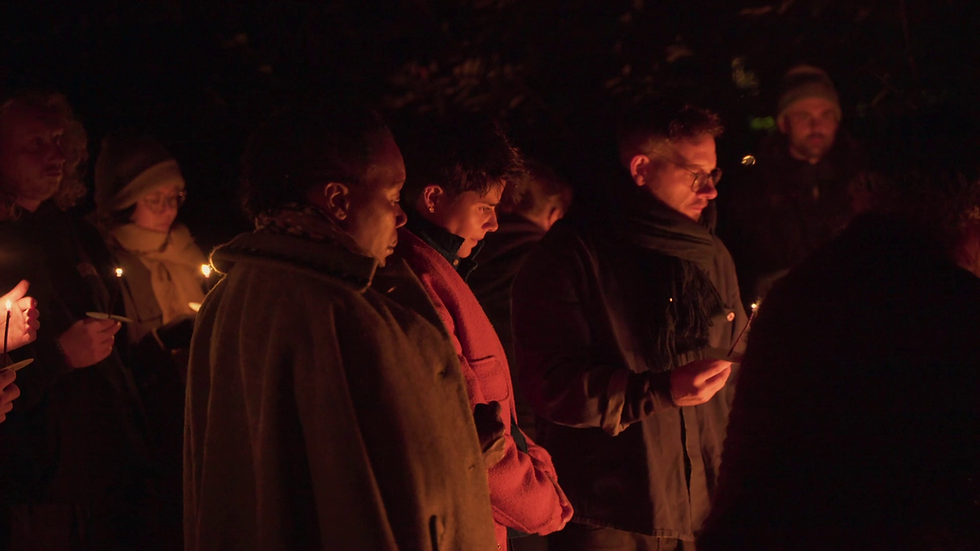 Group of people at night holding candles in a dimly lit setting.