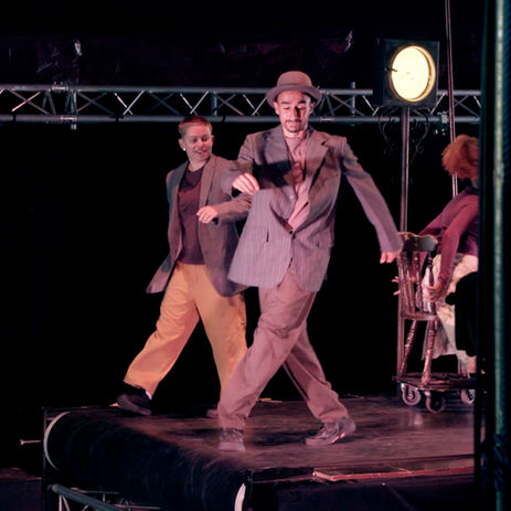 Three performers dancing on a dark stage