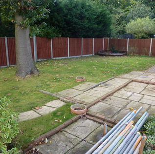 A backyard with a large tree, a paved stone path, and grassy areas