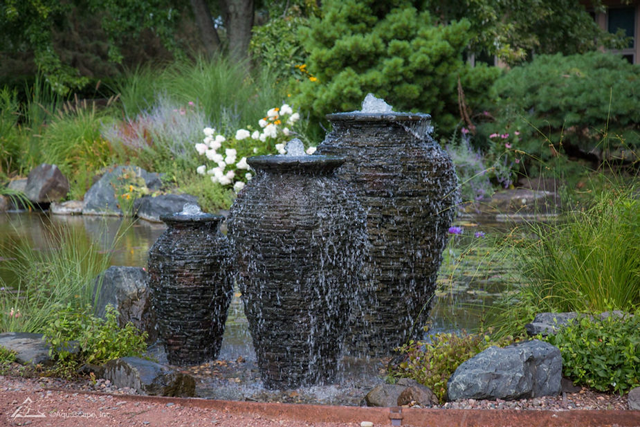 Water feature with a stack of large urns dripping water