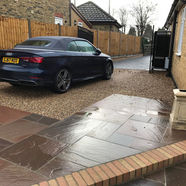 A sleek blue convertible is parked on a gravel driveway