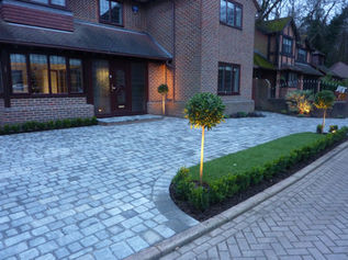 house with a brick driveway and a small lamppost