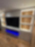 Modern entertainment center with a large flat-screen TV, flanked by open shelves with vertical wood paneling