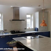 Modern kitchen with a large, white marble island, blue lower cabinets, and copper pendant lights