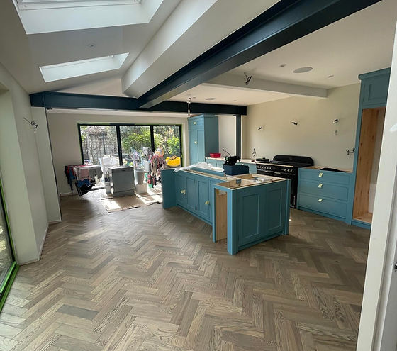 Spacious kitchen with herringbone wood floor, skylights, teal cabinets, and black stove