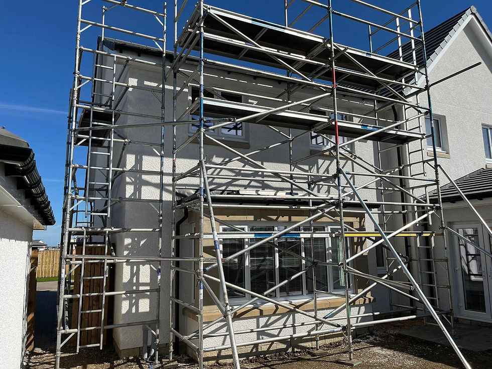 Scaffolding surrounds a two-story house under a clear blue sky