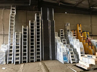 A warehouse interior with stacks of ladders arrayed against a concrete wall
