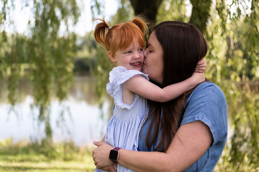 Mum kisses her daugher's cheek Ormskirk photographer outdoor family lifestyle photography.