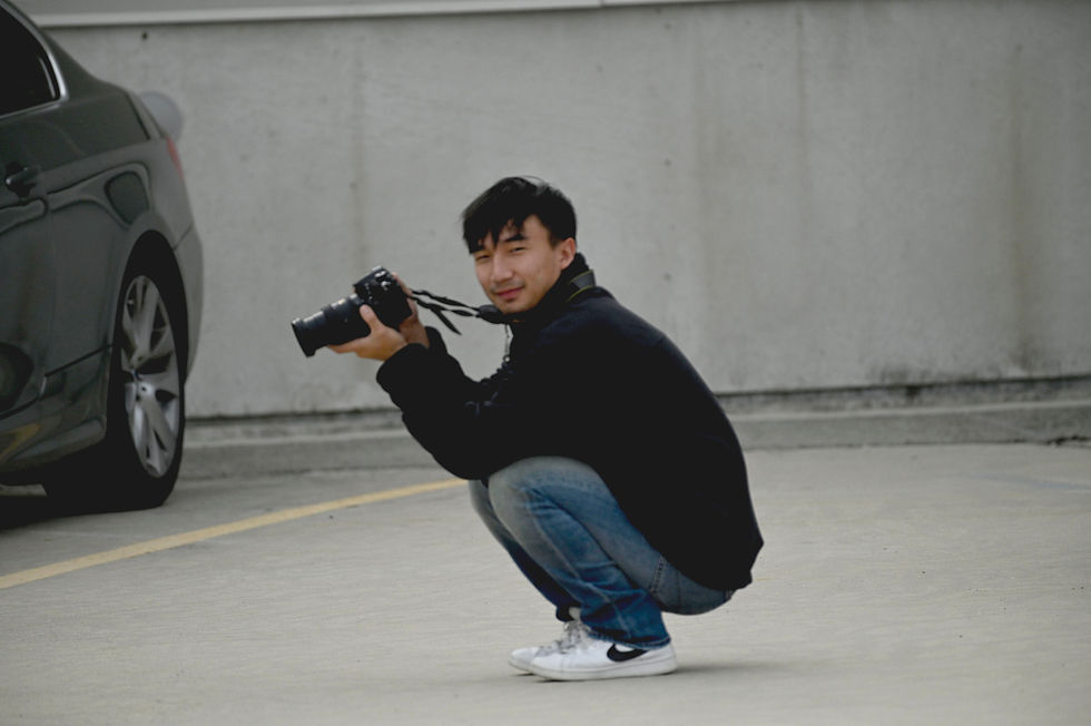 NicK crouches on the pavement, camera in hand, capturing the perfect shot next to a parked car. Friday, Sept. 19, 2025 (Dalton)